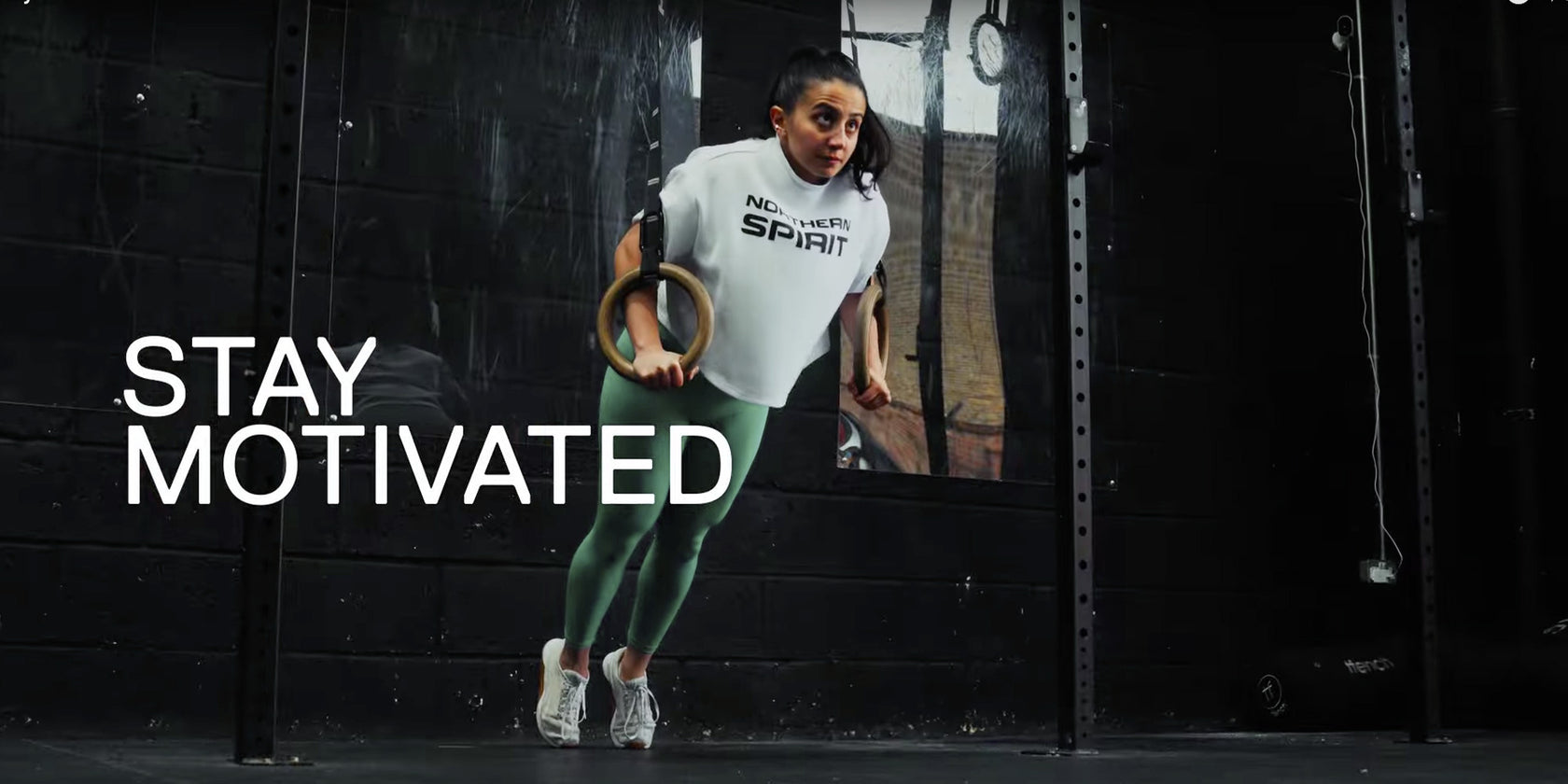Female athlete performing ring dips wearing Northern Spirit oversized tee and leggings during CrossFit® training — Stay Motivated.