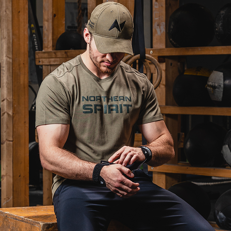 Northern Spirit presents its athlete Nicolas. He's wearing the NS Kraken grips for his gym session. He's also sporting the NS cap in Desert color and the NS SAINT 2.0 t-shirt in Desert color.