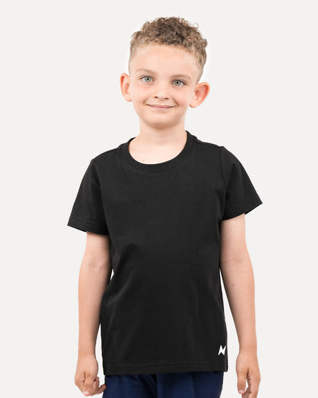 A child wearing a black regular t-shirt, standing against a white background.