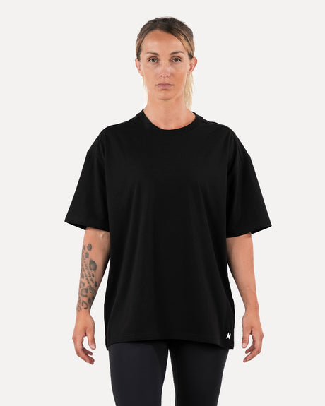A person wearing a black oversized unisex T-shirt.