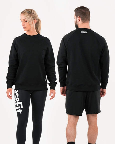 A male and a female model wearing a unisex black sweatshirt from the brand Northern Spirit. The clothing is designed with a regular fit and the models are shown from the back, displaying the sweatshirt's fit and design.
