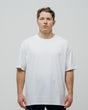 A person wearing a white oversized unisex T-shirt standing against a plain background.