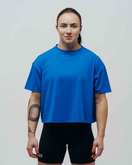 A woman wearing a blue oversized crop top and black shorts.
