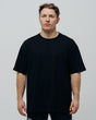 A person wearing a black oversized T-shirt, standing against a plain background.