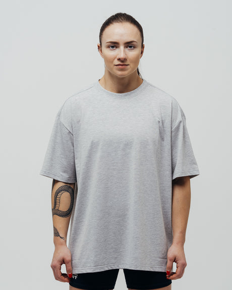 A person wearing a gray oversized T-shirt standing against a light background.