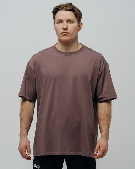 A person wearing a unisex oversized maroon T-shirt.