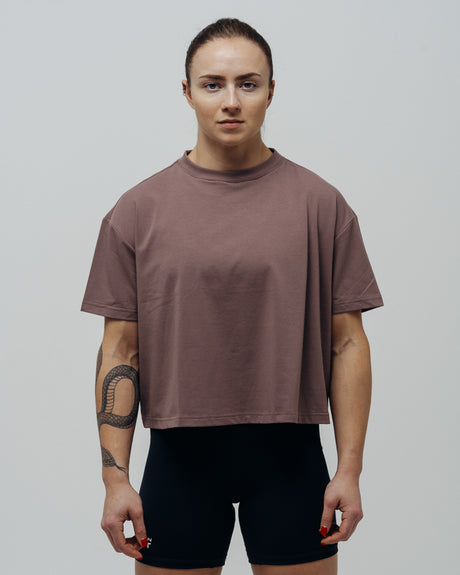 A woman wearing a maroon oversized crop top and black shorts.