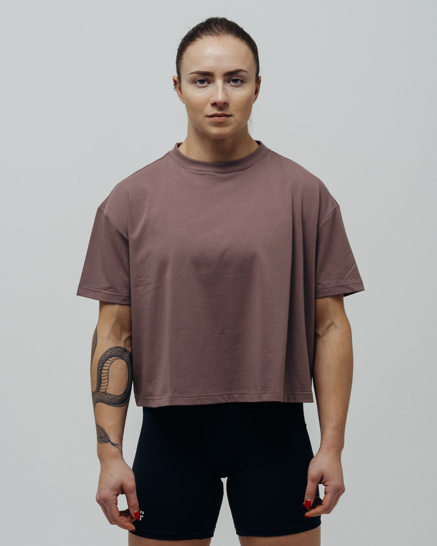 A woman wearing a maroon oversized crop top and black shorts.