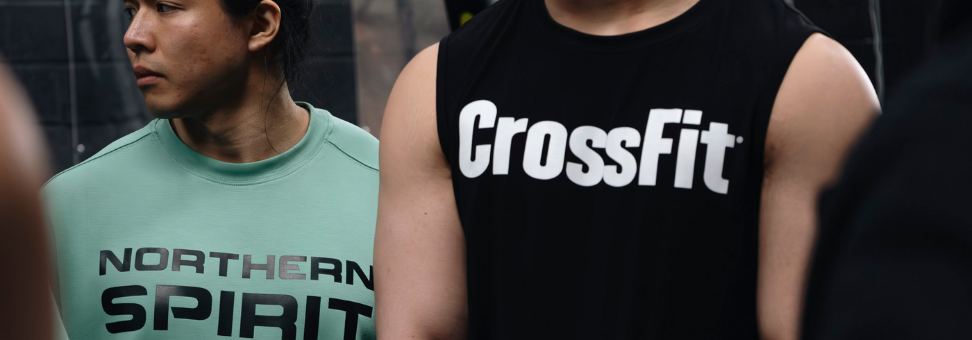 Close-up of athletes wearing Northern Spirit mint green sweatshirt and CrossFit® black tank top during a functional fitness training session.