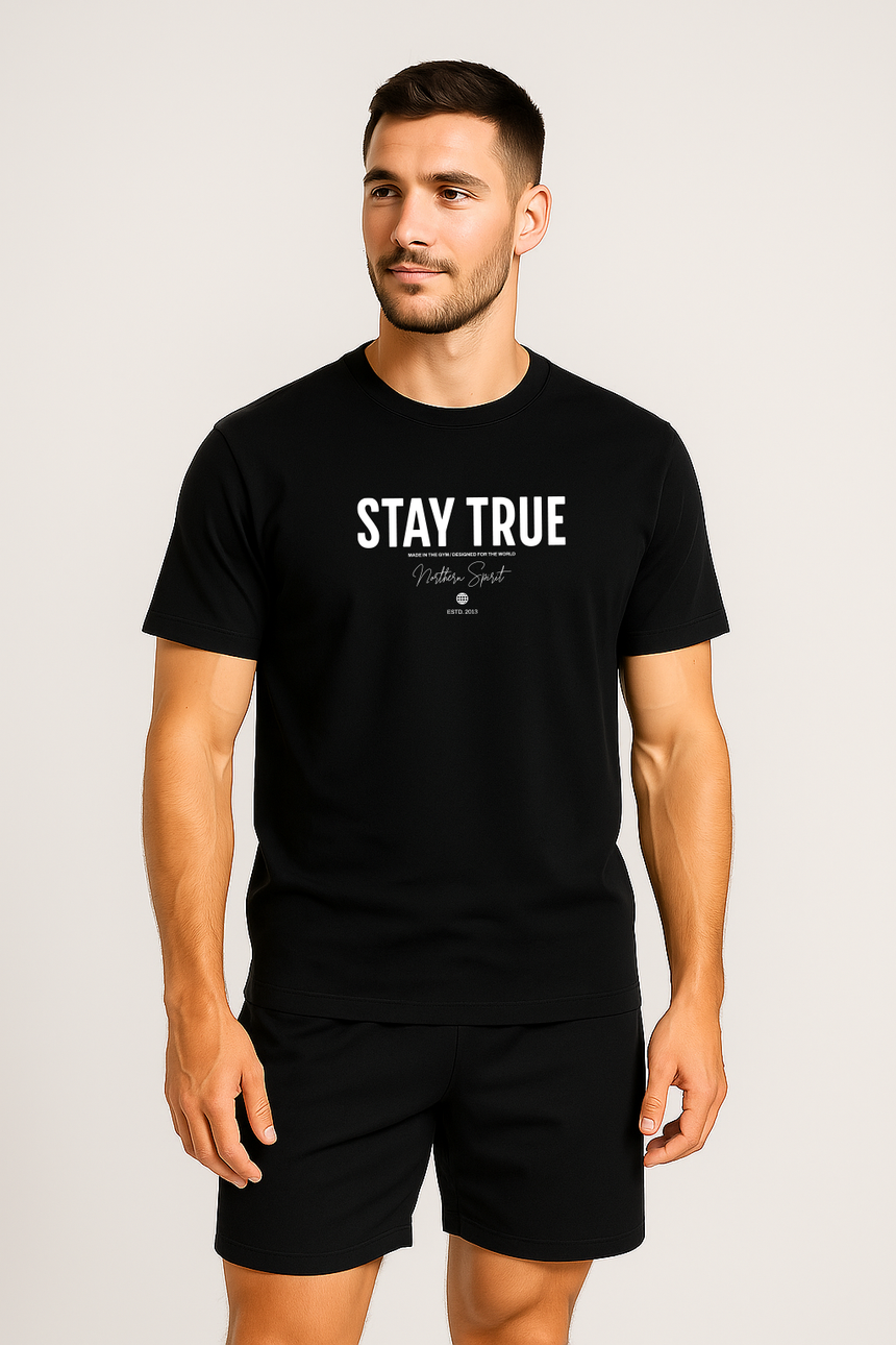 Man wearing a black Northern Spirit Stay True T-shirt standing straight in a studio setting looking slightly to the side