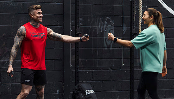 Two athletes fist bumping after a CrossFit® workout, wearing Northern Spirit training apparel — community, strength, and authentic connection in the gym.