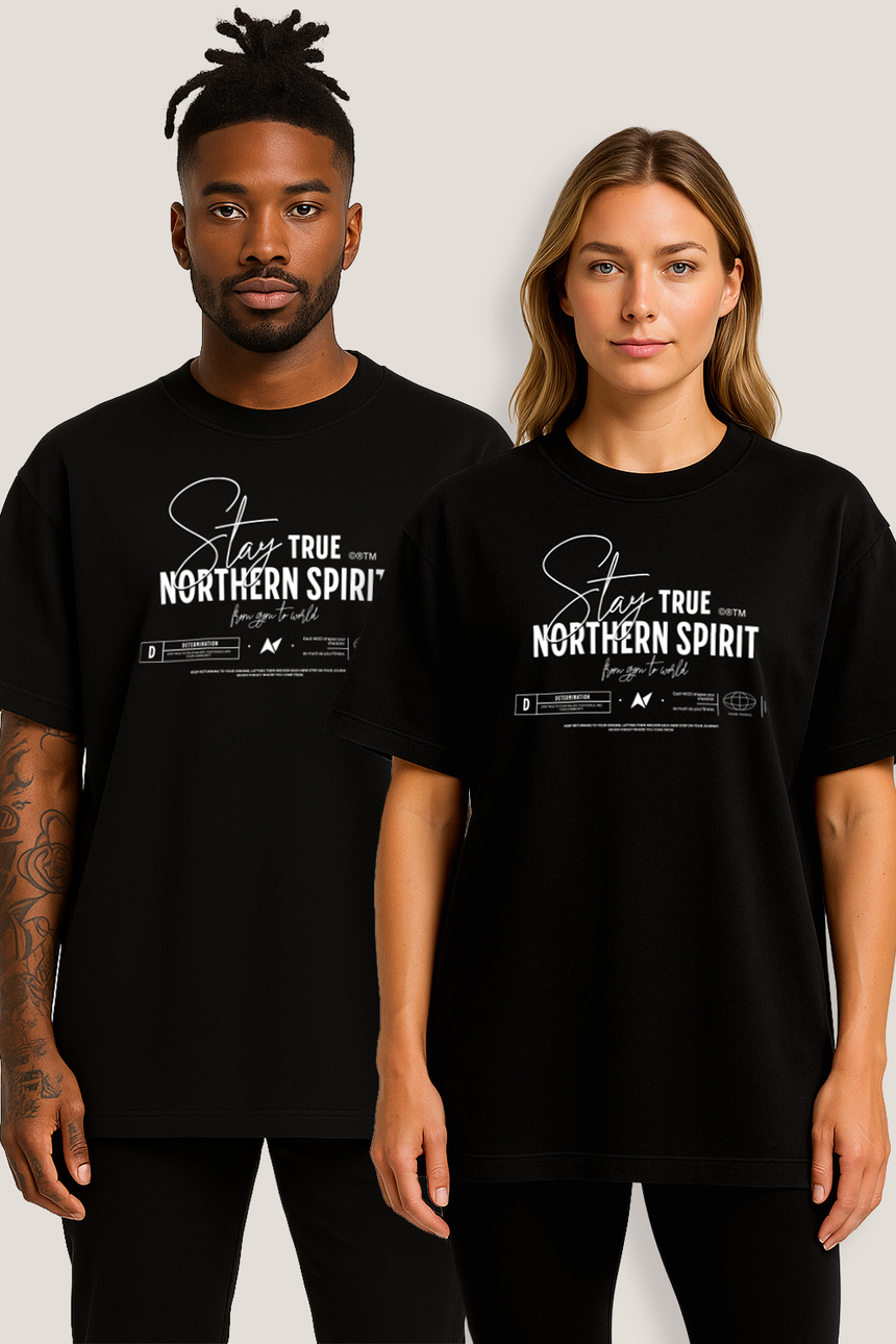 Man and woman wearing matching black Northern Spirit oversized Stay True graphic T-shirts posing together in a studio environment