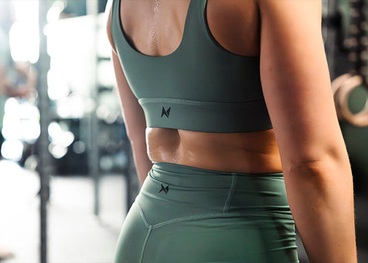 Female athlete wearing Northern Spirit high-waisted leggings and sports bra in khaki during a CrossFit® training session.