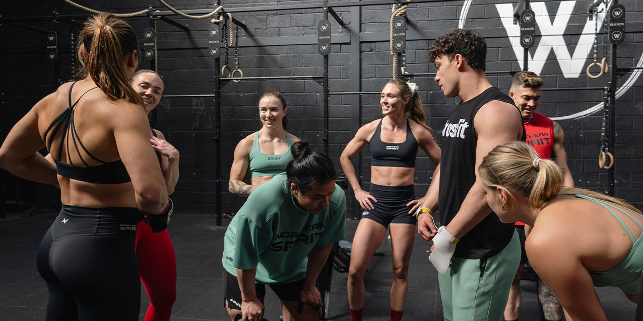 Group of CrossFit® athletes wearing Northern Spirit apparel during a functional training session in a gym, sharing motivation and teamwork.