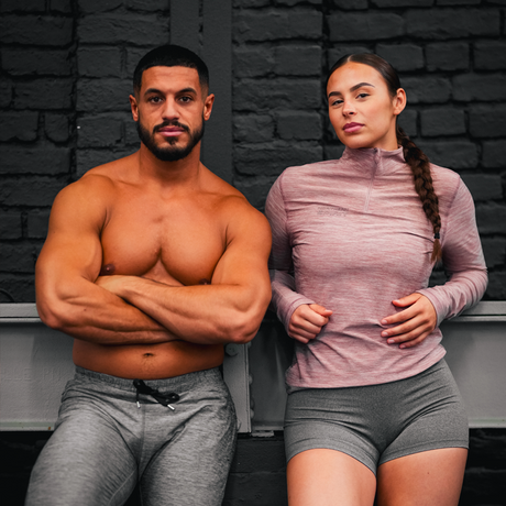 Two athletes are posing for Northern Spirit. The woman is wearing an outfit from the Sharpwear collection, featuring shorts and a long-sleeved zippered top, while the man is wearing jogging from the same collection.
