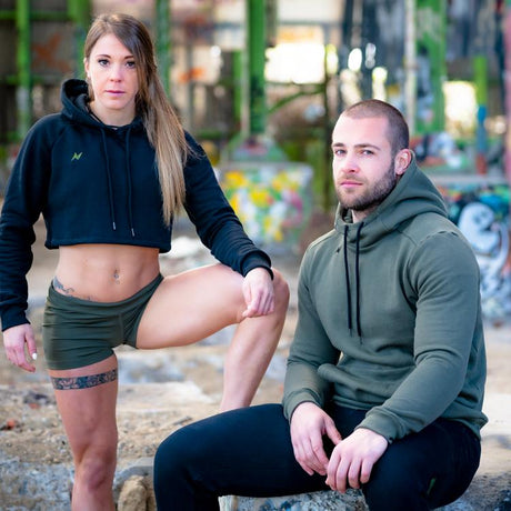 Two athletes (one man and one woman) are dressed in the Techniset collection and are posing in a hangar.