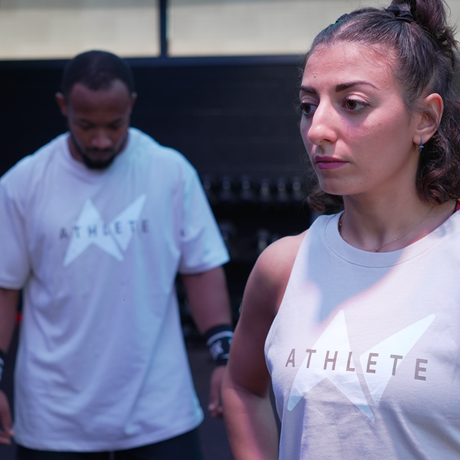 Two athletes are posing for Northern Spirit. They both are wearing a T-shirt and a tank top from the Athlete collection.