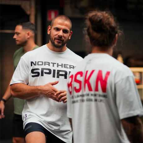 Two athletes are discussing their training together. They're dressed in the oversized t-shirts from the BSKN collection by Northern Spirit.