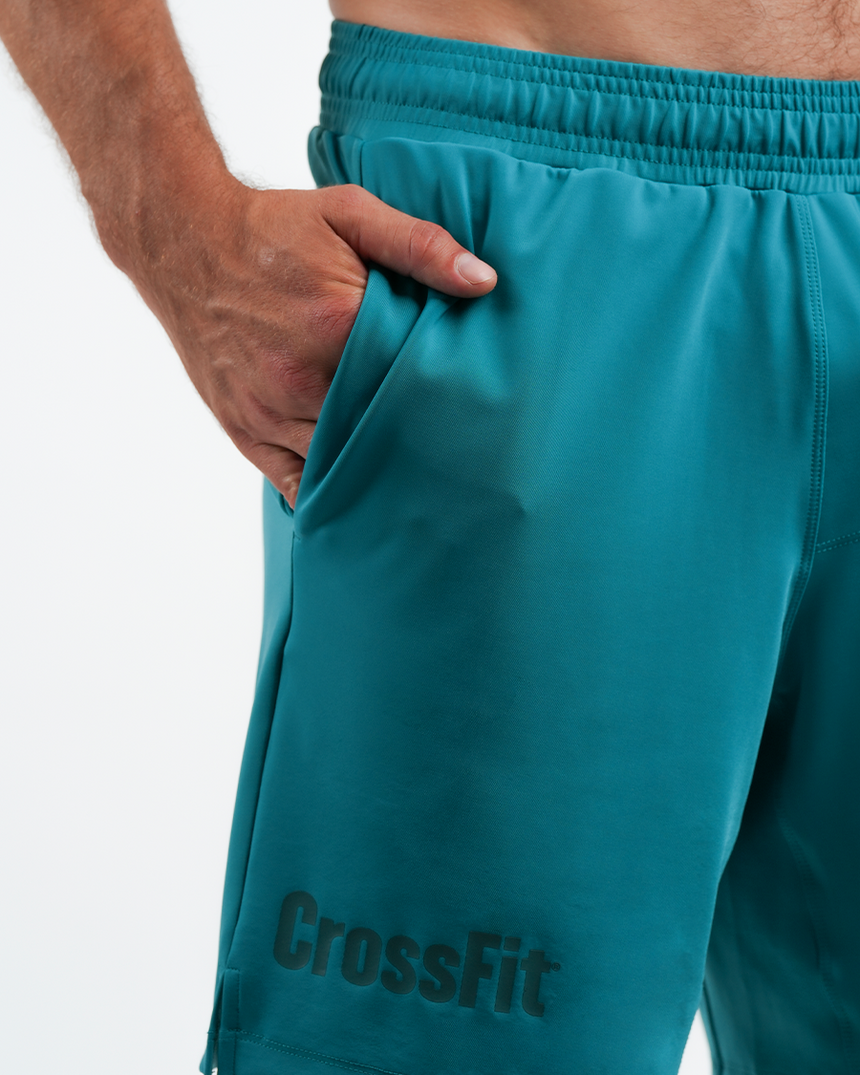 Teal CrossFit shorts with a hand adjusting the waistband on a white background