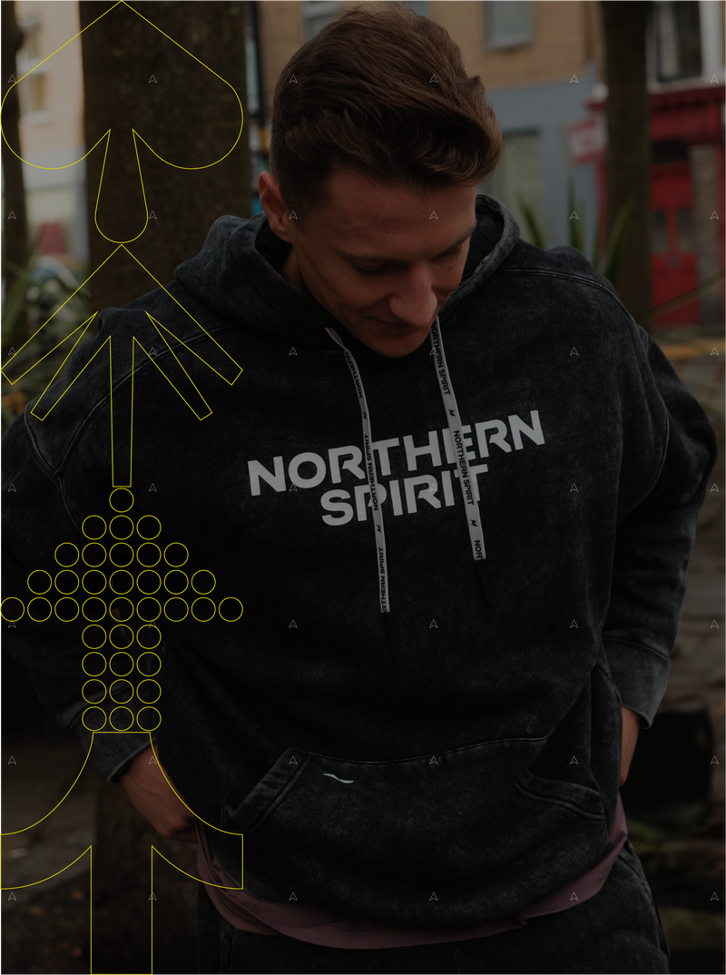 Male athlete outdoors wearing Northern Spirit Cozy Collection washed black hoodie with bold logo.