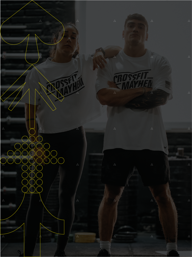 Two athletes standing side by side wearing Northern Spirit x CrossFit® Mayhem oversized white T shirts in a gym setting.