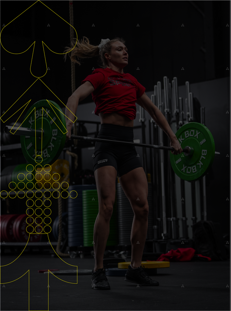 Female weightlifter performing a snatch wearing Northern Spirit red T shirt and black training shorts in a functional fitness gym.