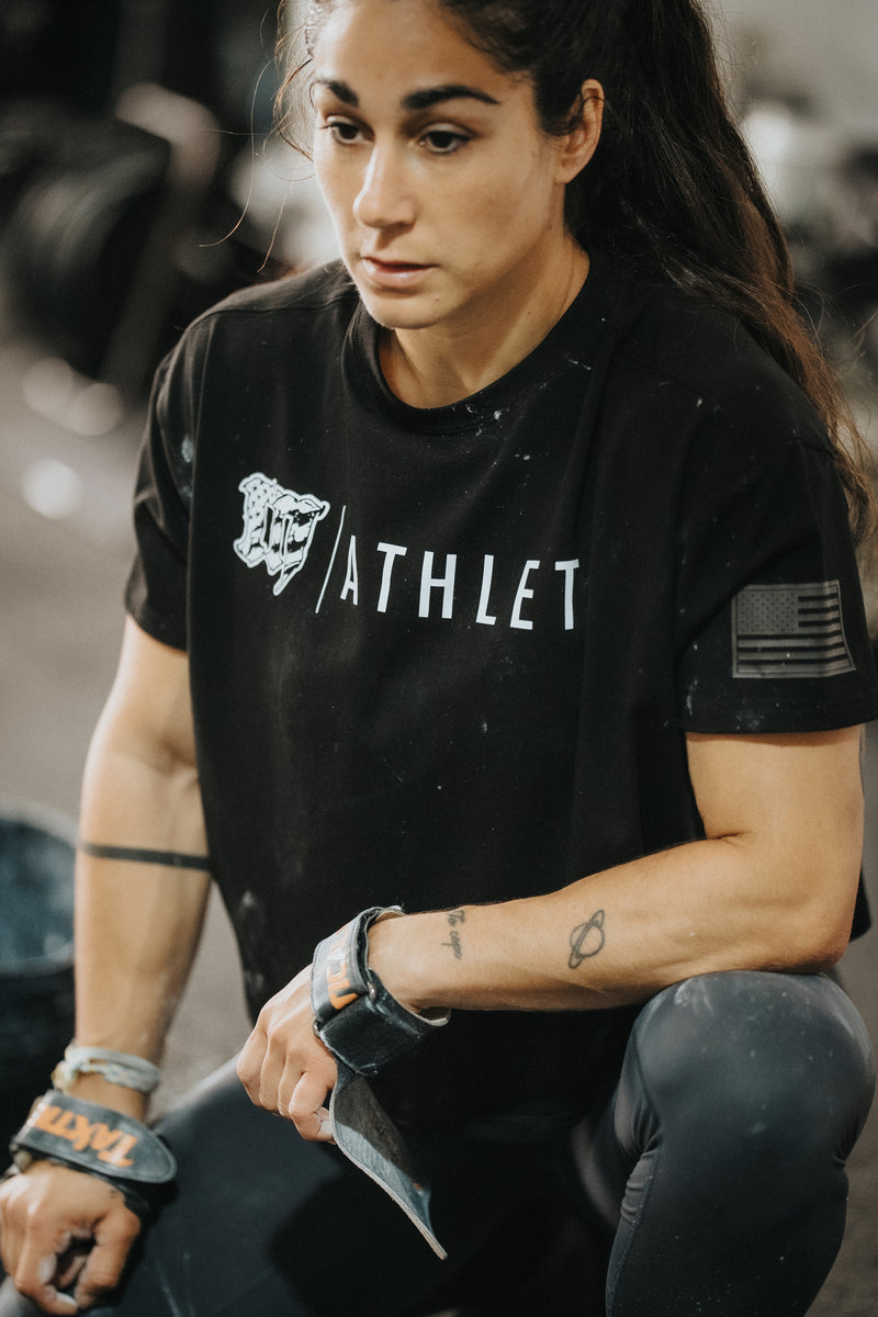 Female CrossFit athlete wearing a black Mayhem ATHLETE tee during functional fitness training in a CrossFit gym