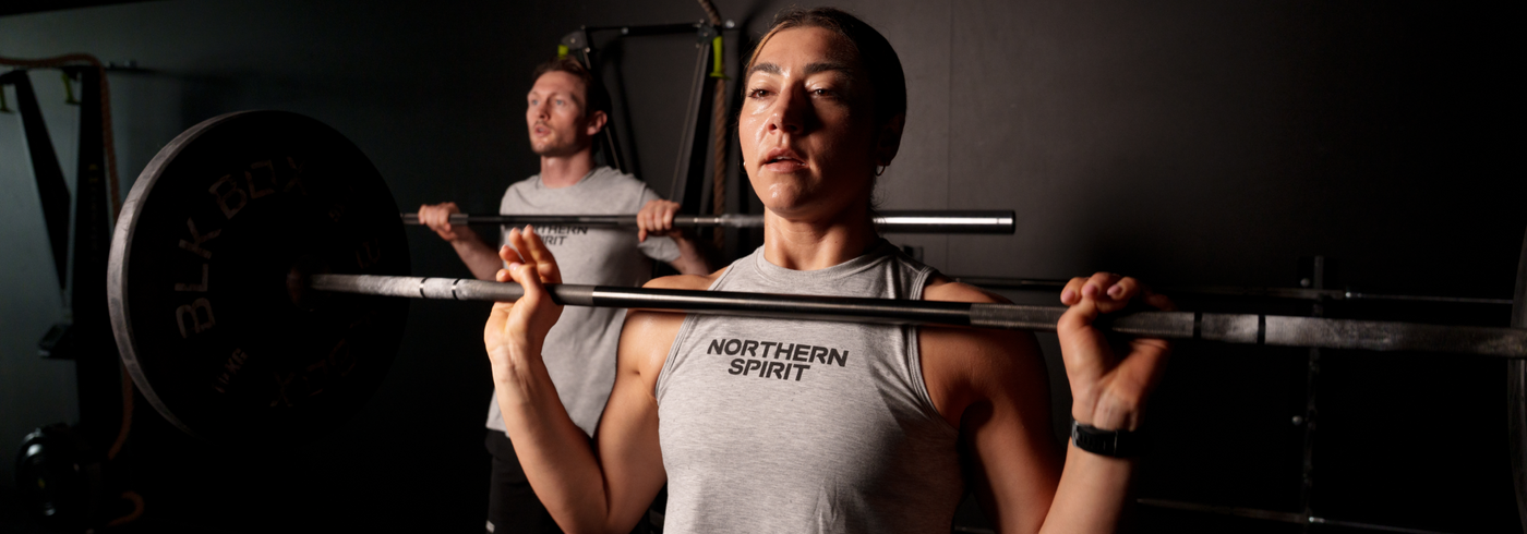 Two people lifting weights in a gym setting