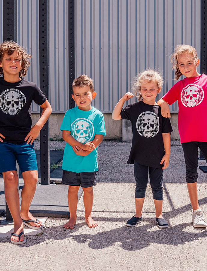 Four children wearing t-shirts with skull designs outdoors.
