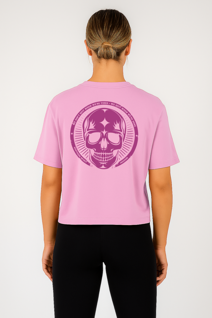 Person wearing a pink t-shirt with a purple skull design on the back, standing against a white background.