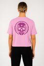 Person wearing a pink t-shirt with a purple skull design on the back, standing against a white background.