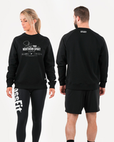 Man and woman wearing black Northern Spirit Stay True oversized sweatshirts shown from the front and back in a bright studio environment