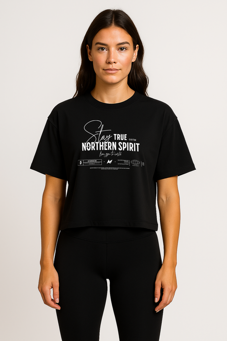 Woman wearing a black Northern Spirit Stay True cropped T-shirt standing upright in a minimalist studio setting