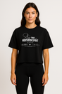 Woman wearing a black Northern Spirit Stay True cropped T-shirt standing upright in a minimalist studio setting